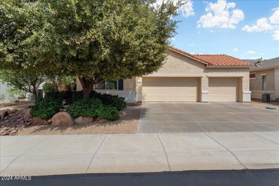 This lovely home is on a private lot at the north boundary of the 55+ Arizona Traditions resort, and has a FULL THREE CAR GARAGE! This mature tree provides welcome shade to the guest bedroom! | Image 1