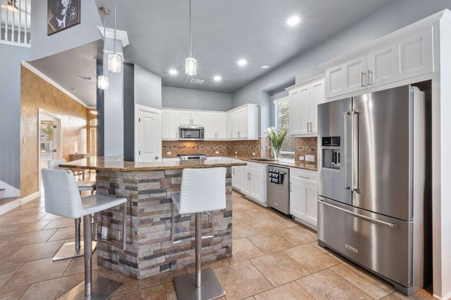 Kitchen area with breakfast bar for food prepping or dining, topped with granite counters, tile backsplash. | Image 4