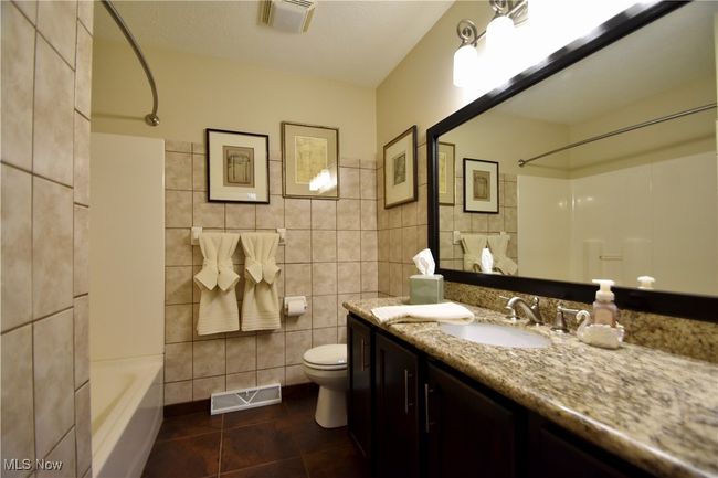 Bathroom with tile walls, toilet, vanity, tile patterned flooring, and tub / shower combination | Image 18