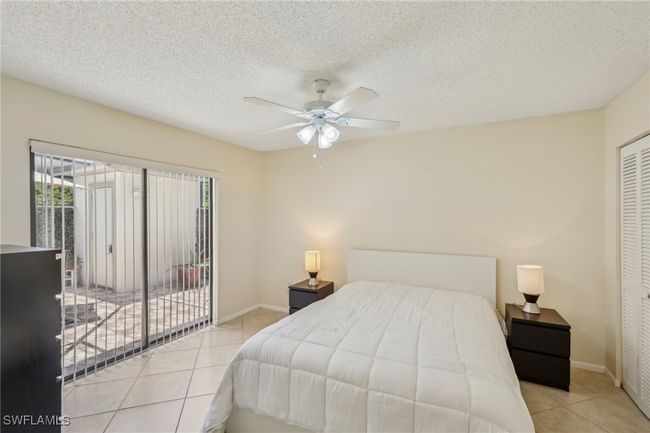 Bedroom featuring light tile patterned floors, access to outside, a textured ceiling, a ceiling fan, and a closet | Image 18