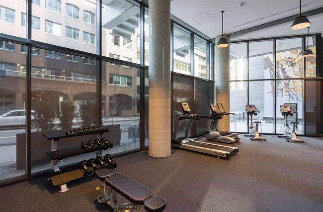 Workout area with a high ceiling, carpet floors, and a wall of windows | Image 9