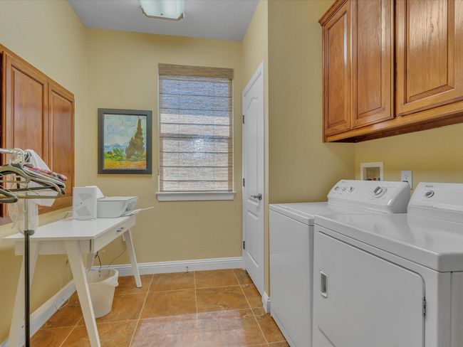 Laundry area with cabinet space, washer and clothes dryer, baseboards, and light tile patterned floors | Image 29