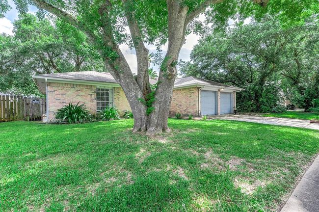 Brick exterior with a two-car garage. It's surrounded by mature trees offering plenty of shade and curb appeal. | Image 4