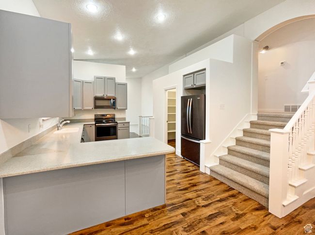 Kitchen featuring visible vents, gray cabinetry, arched walkways, and appliances with stainless steel finishes | Image 12