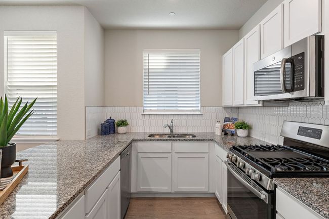 Kitchen featuring white cabinets, a sink, light stone counters, and appliances with stainless steel finishes | Image 11