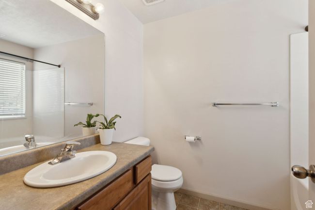 Full bathroom with toilet, vanity, tile patterned flooring, a shower, and baseboards | Image 21