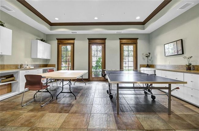 Game room featuring a tray ceiling, crown molding, healthy amount of natural light, recessed lighting, and stone finish flooring | Image 46