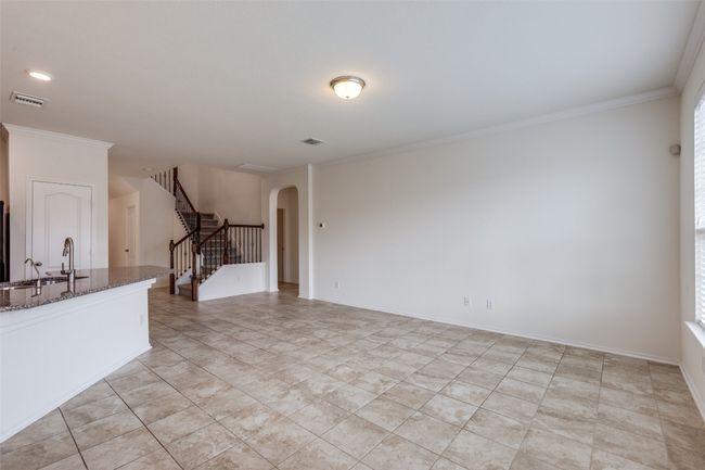 Unfurnished living room featuring a sink, ornamental molding, stairway, and arched walkways | Image 6