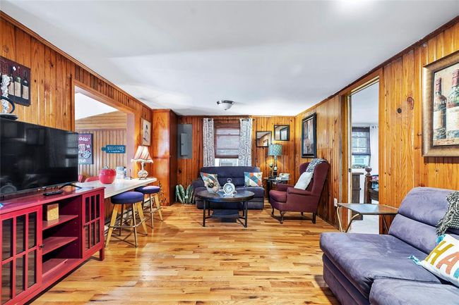 Living room with electric panel, light hardwood / wood-style floors, and wood walls | Image 8