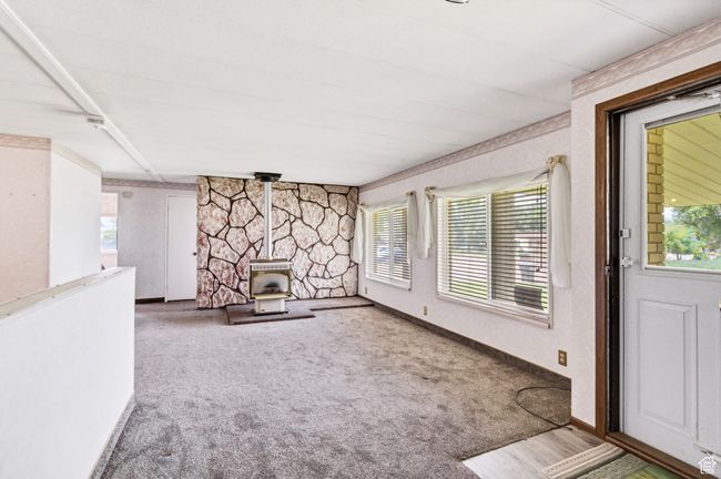 Unfurnished living room with a gas stove, carpet, and baseboards | Image 6