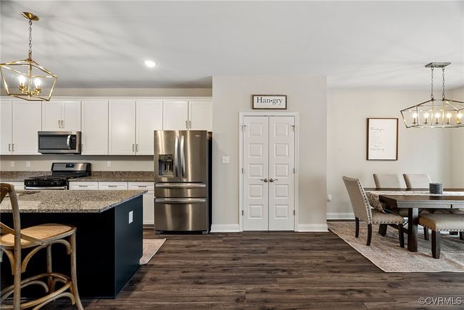 Kitchen with pendant lighting, a breakfast bar, dark hardwood / wood-style floors, light stone counters, and stainless steel appliances | Image 7