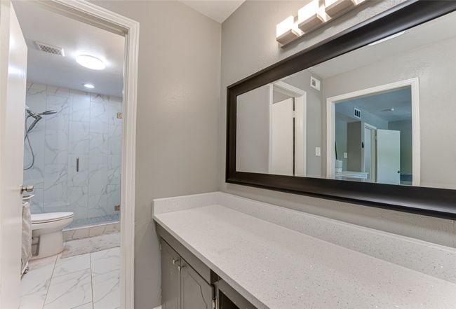 Bathroom with vanity, toilet, a marble finish shower, visible vents, and marble finish floor | Image 15
