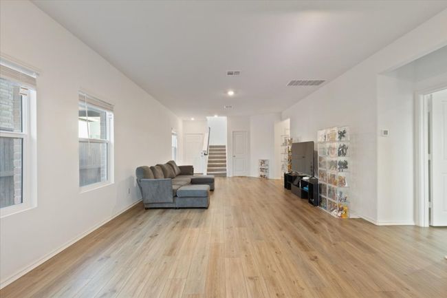 Living room with visible vents, light wood-style flooring, baseboards, and stairway | Image 4