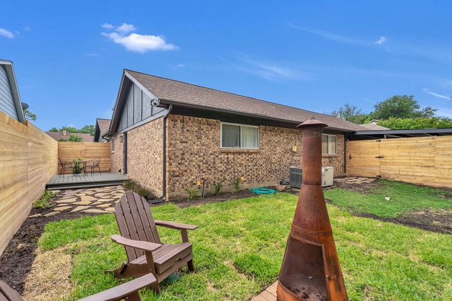 Rear view of property with brick siding, a wooden deck, a fenced backyard, cooling unit, and a lawn | Image 37