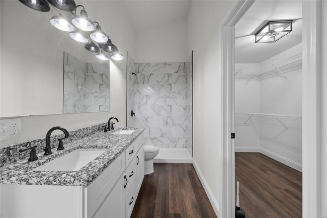 Full bathroom featuring double vanity, wood finished floors, walk in shower, a walk in closet, and a sink | Image 39