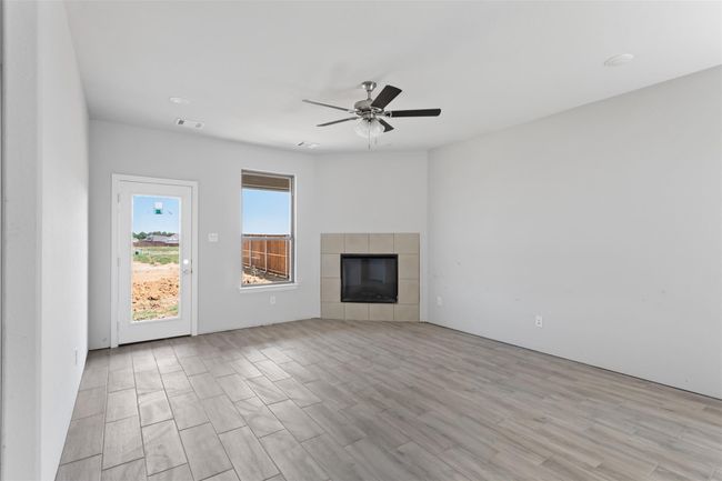 Unfurnished living room with a fireplace, light hardwood / wood-style flooring, and ceiling fan | Image 11