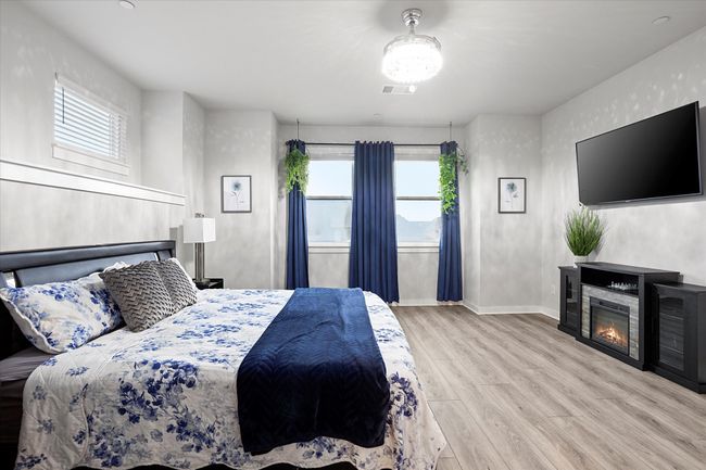Bedroom featuring light wood finished floors, multiple windows, and a glass covered fireplace | Image 13