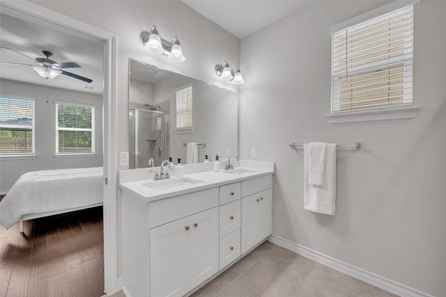 Full bath featuring a shower stall, ceiling fan, double vanity, and baseboards | Image 10