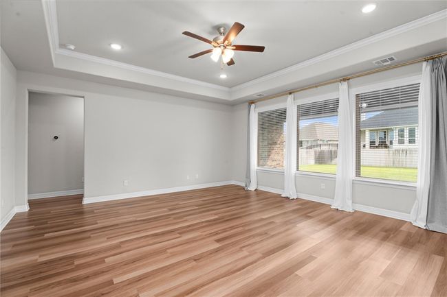 Unfurnished room featuring a ceiling fan, a tray ceiling, crown molding, light wood finished floors, and baseboards | Image 5