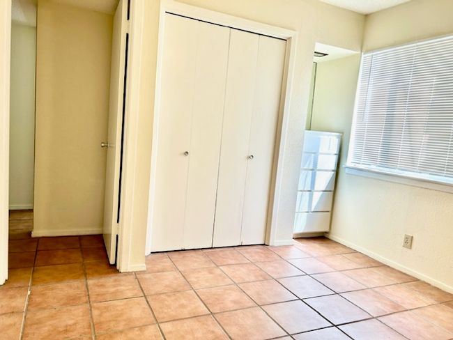 Unfurnished bedroom featuring light tile patterned flooring, baseboards, and a closet | Image 9