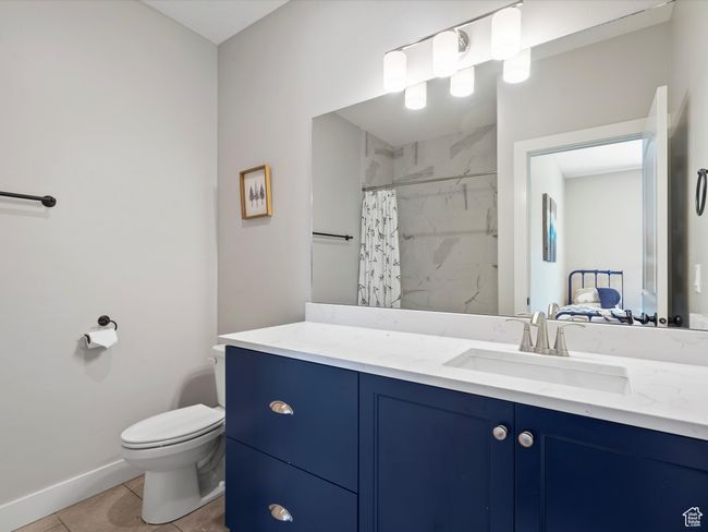 Bathroom featuring toilet, baseboards, curtained shower, tile patterned floors, and vanity | Image 42