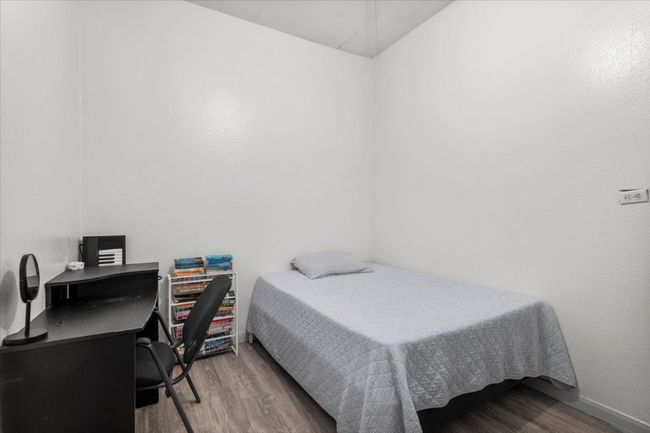 Bedroom with wood finished floors and an office area | Image 7