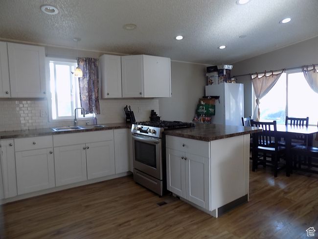 Kitchen with white refrigerator, stainless steel range with gas cooktop, sink, and white cabinets | Image 7
