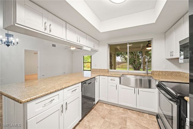 Kitchen with appliances with stainless steel finishes, ceiling fan, a peninsula, white cabinets, and light stone counters | Image 5