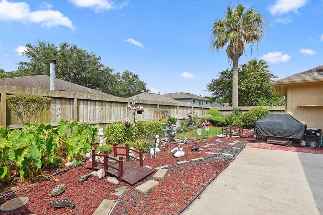 Backyard retreat with lush landscaping, rock-lined garden, charming bridge, and tranquil fountain — creating your own private escape for peace and relaxation. | Image 21