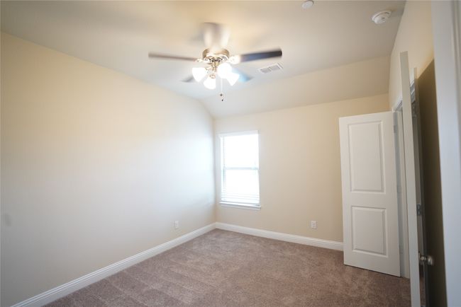 Carpeted empty room featuring ceiling fan, vaulted ceiling, and a smoke detector | Image 25