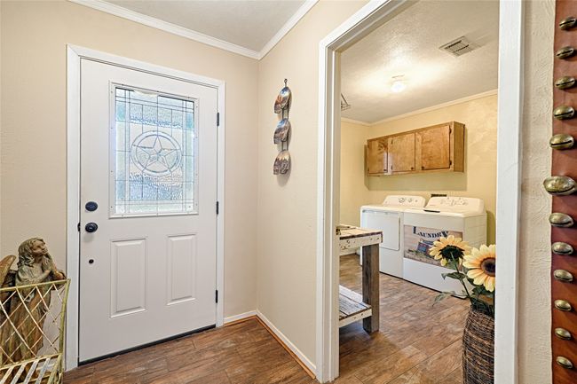 Foyer entrance featuring a textured ceiling, washing machine and dryer, dark hardwood / wood-style floors, and crown molding | Image 16