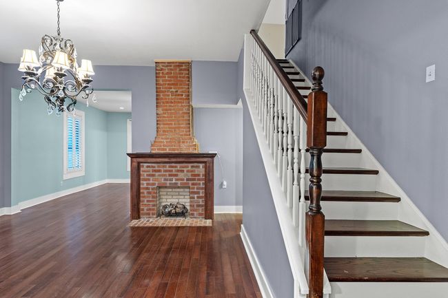 Staircase with wood finished floors, a chandelier, baseboards, and a fireplace | Image 17
