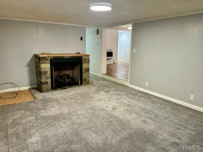 Living room with heating unit, crown molding, a fireplace, and carpet floors | Image 23