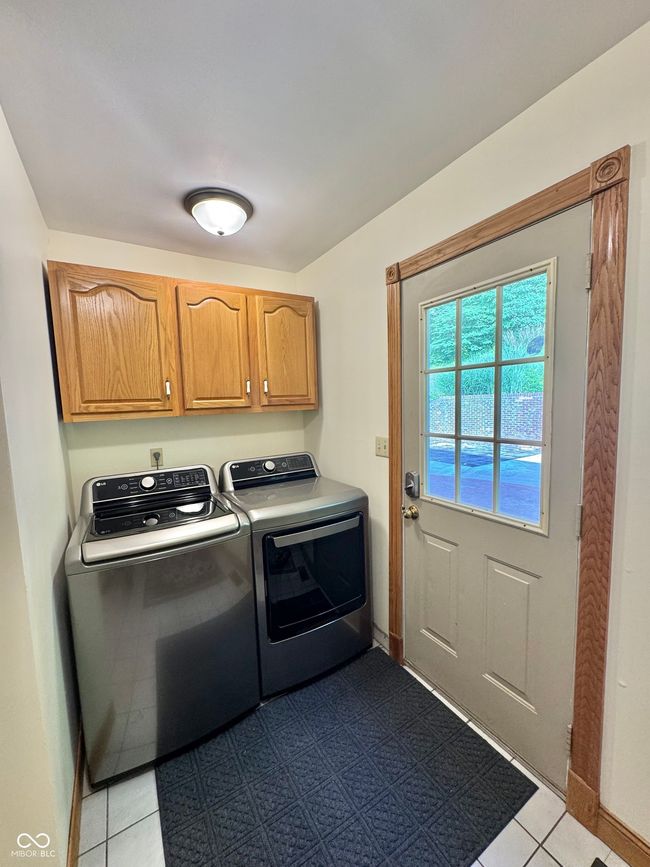 laundry room featuring independent washer and dryer, cabinet space, light tile patterned flooring, and baseboards | Image 51