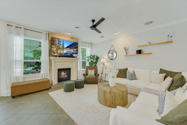Living area featuring tile patterned flooring, a glass covered fireplace, ceiling fan, and ornamental molding | Image 6