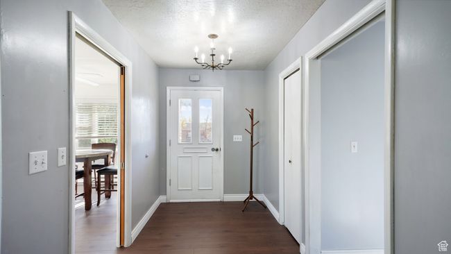 Foyer entrance featuring a chandelier, dark wood finished floors, a textured ceiling, and baseboards | Image 9