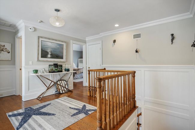 Hall featuring visible vents, wood finished floors, an upstairs landing, and ornamental molding | Image 22