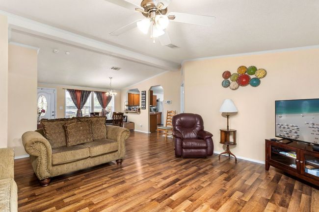 Living room with lofted ceiling with beams, wood finished floors, arched walkways, and visible vents with Central Heat and air, and open to dining area | Image 21
