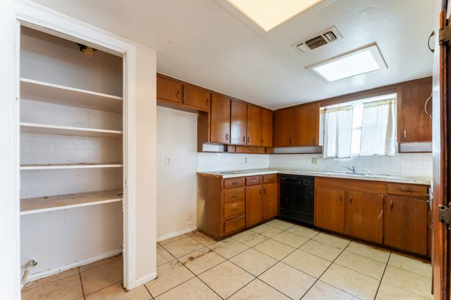 Kitchen with visible vents, brown cabinets, light countertops, and black dishwasher | Image 10