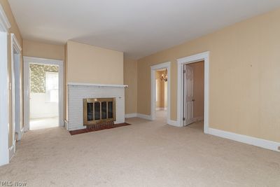 Unfurnished living room featuring light carpet and a brick fireplace | Image 2