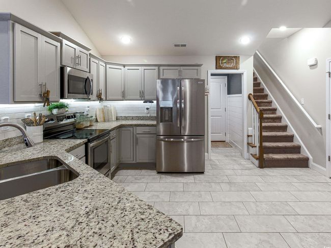 Kitchen featuring vaulted ceiling, appliances with stainless steel finishes, sink, tasteful backsplash, and light stone counters | Image 11