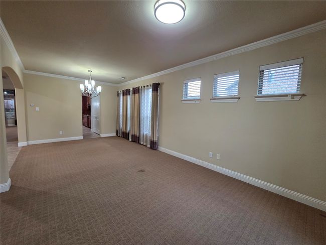 Unfurnished room featuring a chandelier, crown molding, arched walkways, carpet flooring, and plenty of natural light | Image 8