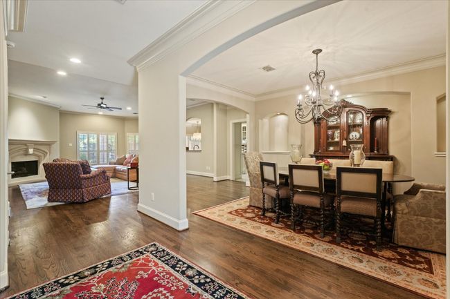 Dining area featuring arched walkways, ceiling fan, dark wood-style floors, a chandelier, and crown molding | Image 7
