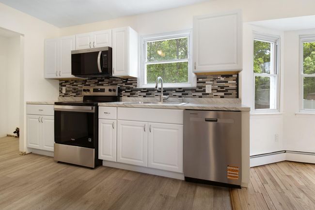 Kitchen with appliances with stainless steel finishes, a sink, light wood-style floors, and tasteful backsplash | Image 13