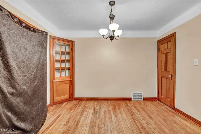 Spare room featuring a notable chandelier, baseboards, visible vents, and light wood finished floors | Image 9