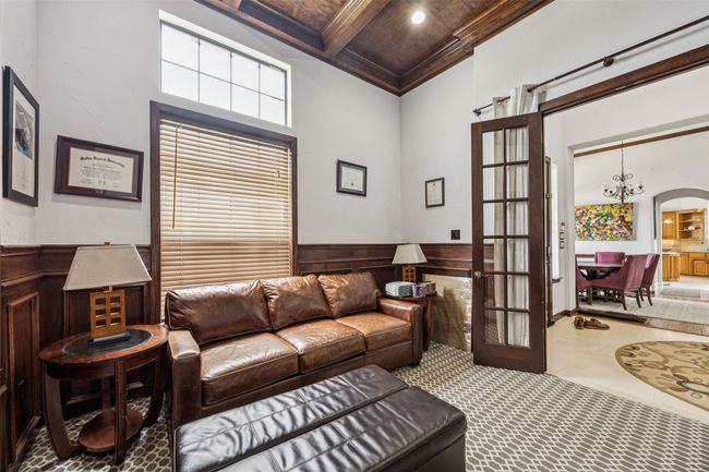 Living area with coffered ceiling, a high ceiling, a chandelier, wainscoting, and french doors | Image 11