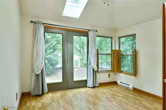 Spare room featuring baseboard heating, a skylight, light wood-type flooring, and lofted ceiling | Image 15
