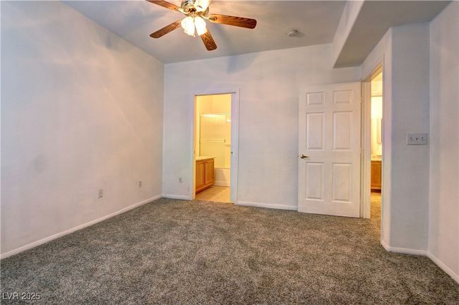 Unfurnished bedroom featuring light carpet, baseboards, connected bathroom, and a ceiling fan | Image 13