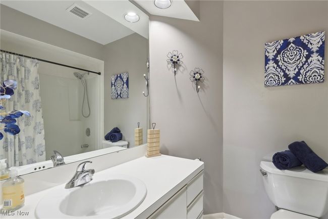 Bathroom with toilet, visible vents, vanity, and curtained shower | Image 24