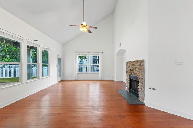 View of the living room with high vaulted ceiling, a fireplace, wood-flooring | Image 14